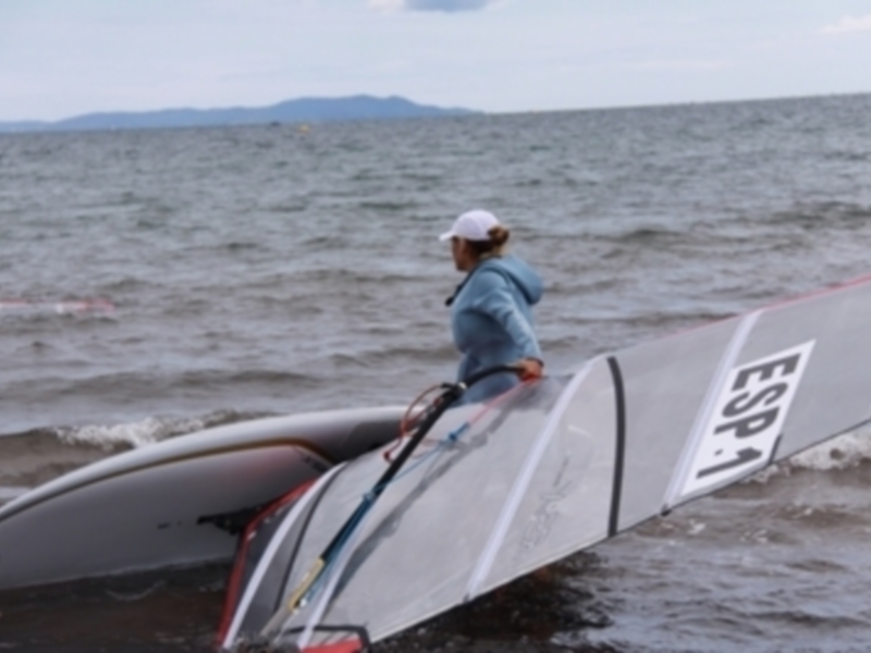 Una persona en un windsurfing en el mar, con una señal de identificación 'ESP1' en la parte trasera del windsurf.