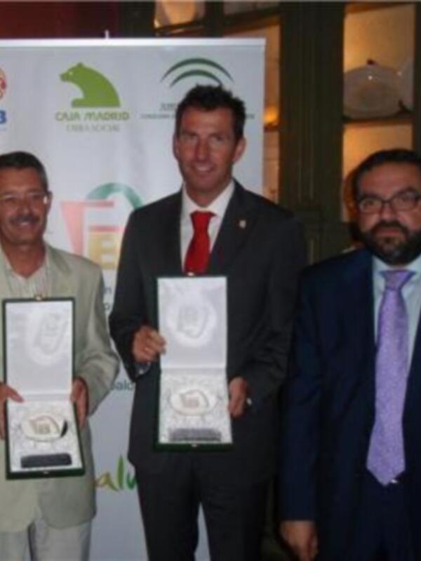 Tres hombres posan con placas de reconocimiento en un evento formal.