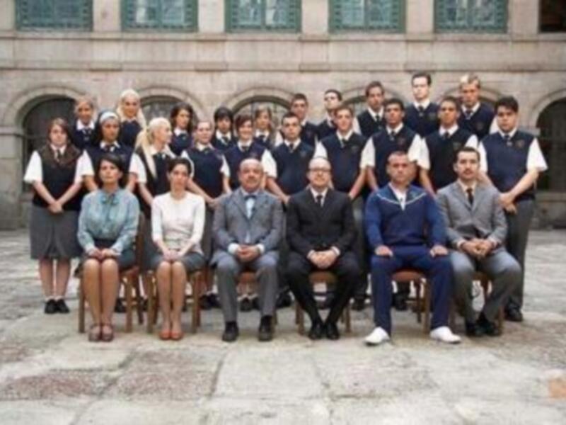 Grupo de personas en uniforme escolar posando en un patio de edificio histórico.