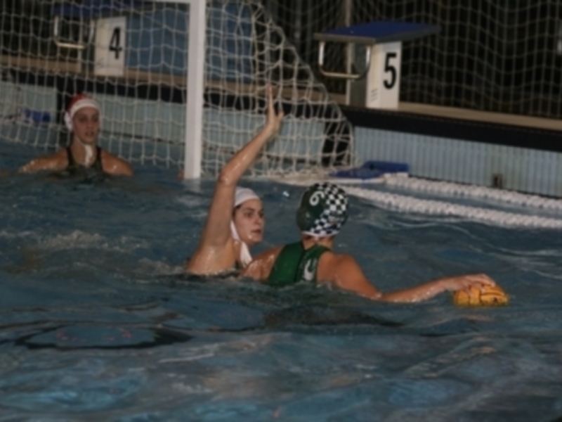 Jugadoras de waterpolo en acción en un partido nocturno.