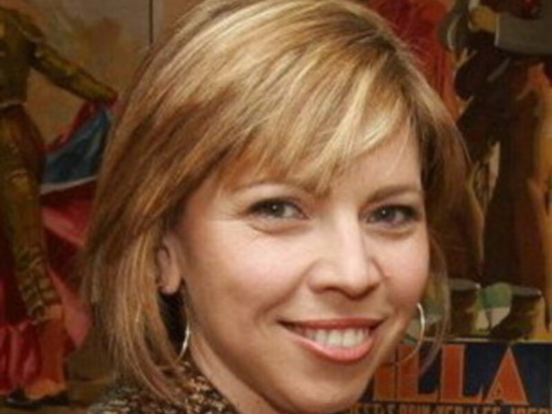 Una mujer con cabello largo y rubio, posando frente a un fondo colorido con letras grandes.