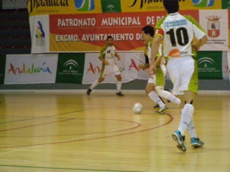 Jugadores de fútbol sala en acción durante un partido en un pabellón deportivo.