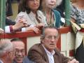 Spectators enjoying a bullfighting event, with a man in a brown jacket leaning on the railing.