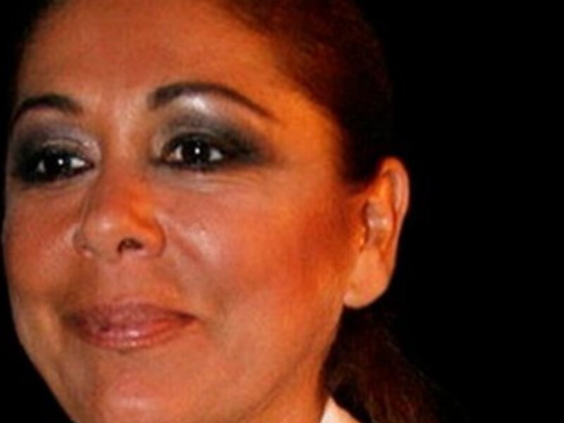 Retrato de mujer con maquillaje elegante y cabello recogido, vistiendo una chaqueta con detalles brillantes.