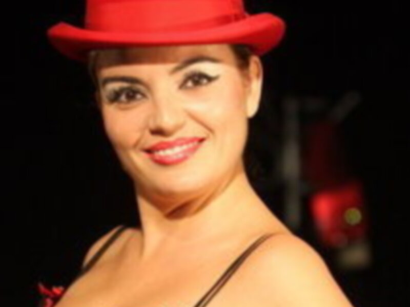 Actriz con traje rojo y sombrero de copa en escenario iluminado