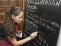 Una camarera escribe en un tablero de menú de un restaurante, que incluye platos como gazpacho, empanada de queso y empanada de atún.