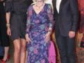 Una mujer vestida con un vestido floral posa junto a una mujer vestida de negro y un hombre vestido de traje.