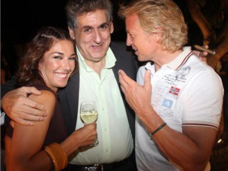 Tres personas disfrutan de una noche festiva, compartiendo risas y un vaso de champán.