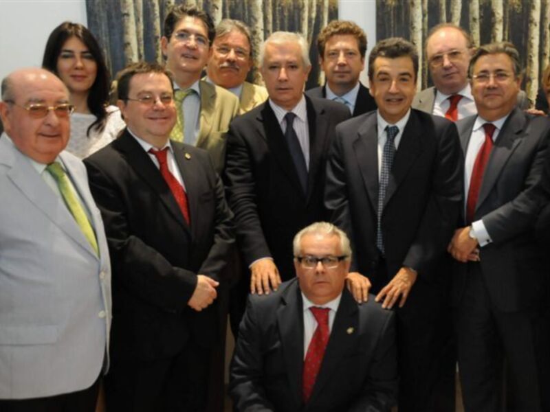 Grupo de hombres en trajes y corbatas posando para una foto en un entorno formal.