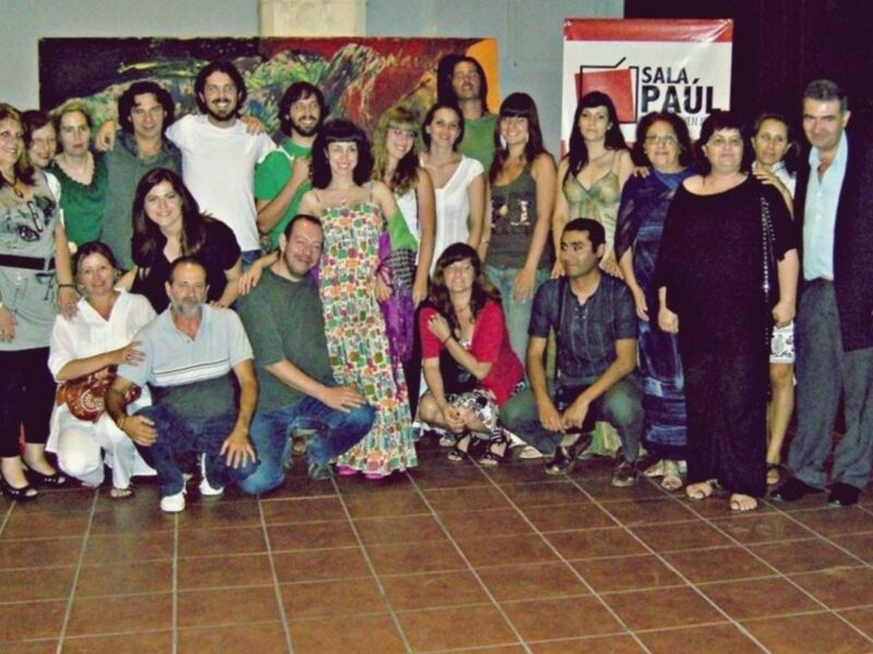 Grupo de personas posando para una foto en Sala Pau l, con un lienzo abstracto en el fondo.