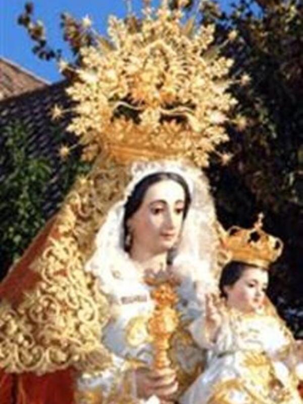Imagen de una Virgen con un niño en sus brazos, vestida con trajes tradicionales y coronada de oro.
