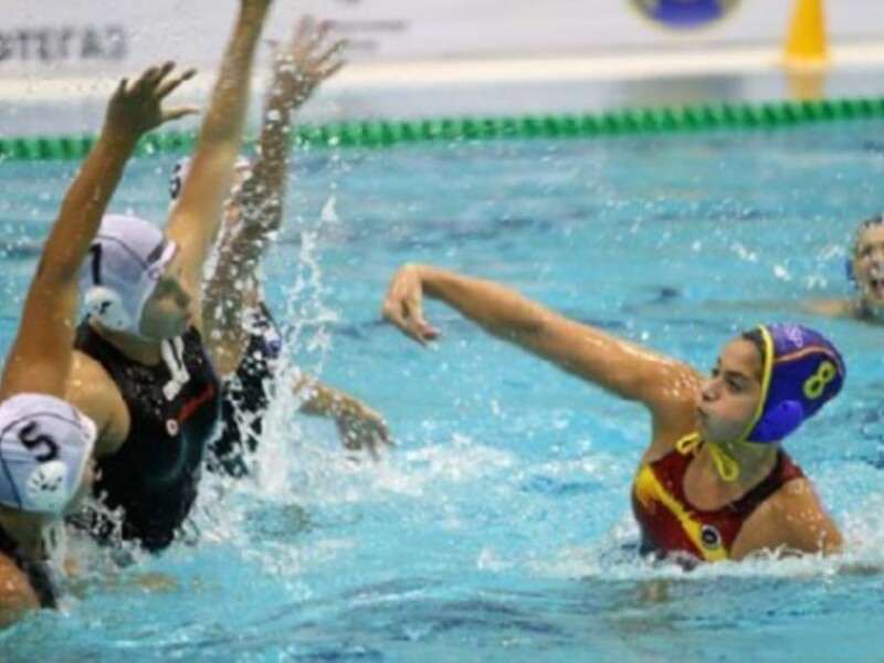 Jugadoras de waterpolo en acción durante un partido en una piscina.
