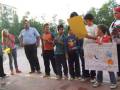 Niños y adultos participan en una actividad al aire libre, con carteles y pancartas en español.