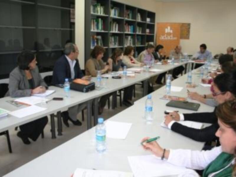 Reunión de trabajo en una biblioteca con participantes sentados alrededor de una mesa.