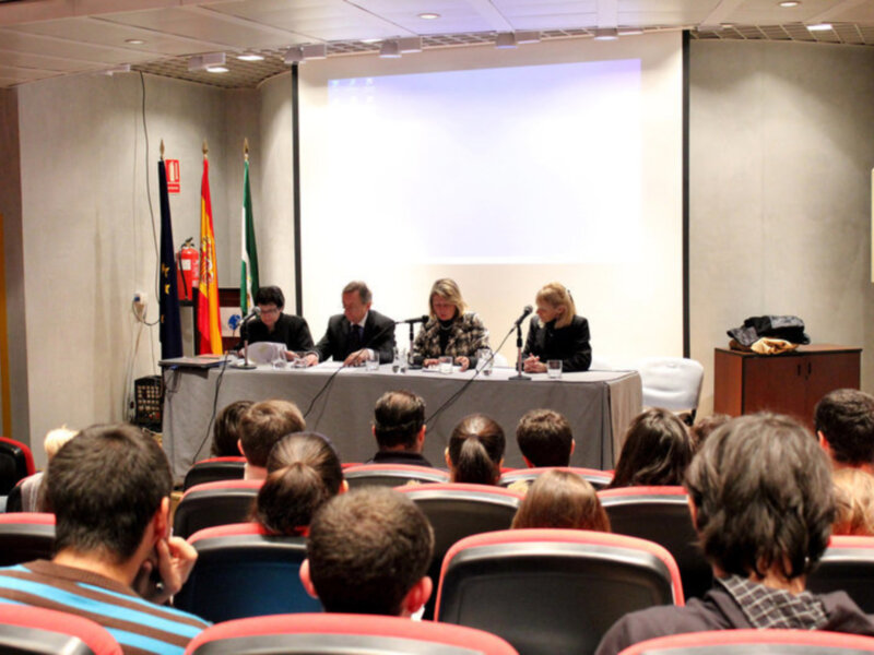 Conferencia en sala de conferencias con panelistas y audiencia atenta.