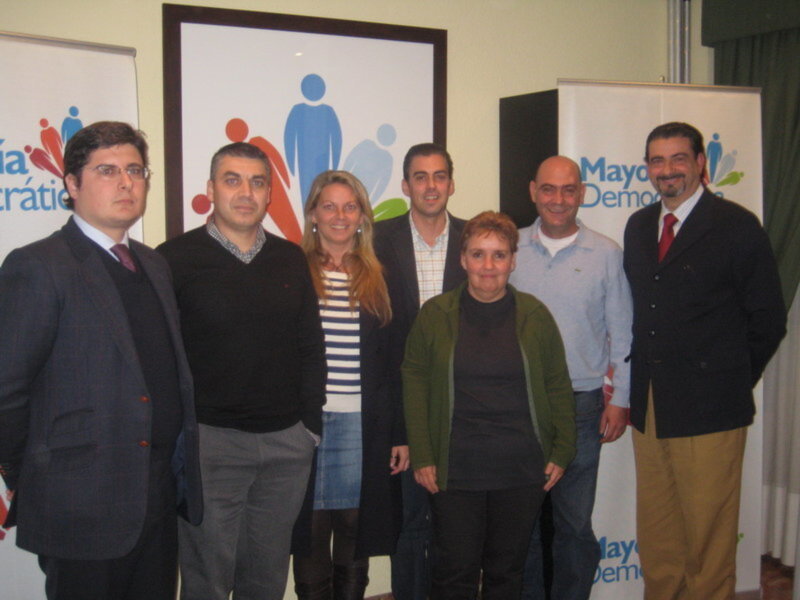 Grupo de personas posando frente a un fondo con logotipos de organizaciones.