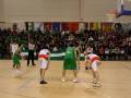Jugadores en acción durante un partido de baloncesto, con banderas nacionales y espectadores en el fondo.