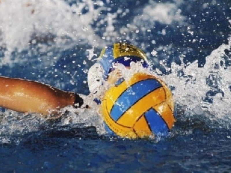 Jugador de waterpolo en acción, golpeando el balón con fuerza mientras el agua se estalla alrededor.