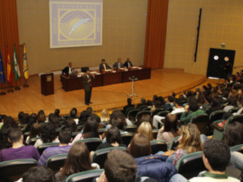 Conferencia en un auditorio lleno de estudiantes y profesores en un evento académico.