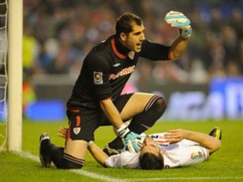Un portero celebra mientras un jugador rival cae al suelo en un partido de fútbol.