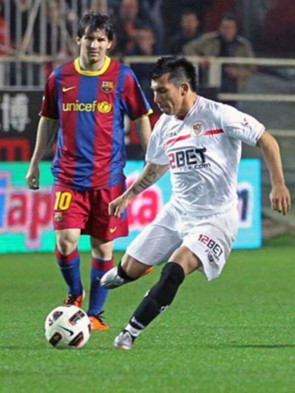 Jugador en blanco driblando el balón durante un partido de fútbol.