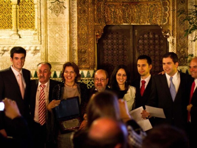 Celebración en el Salón de los Reyes Cristianos, Alcázar de Sevilla, con un grupo de personas posando para una foto.