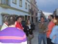 Grupo de personas en una calle de pueblo discutiendo y observando su entorno.