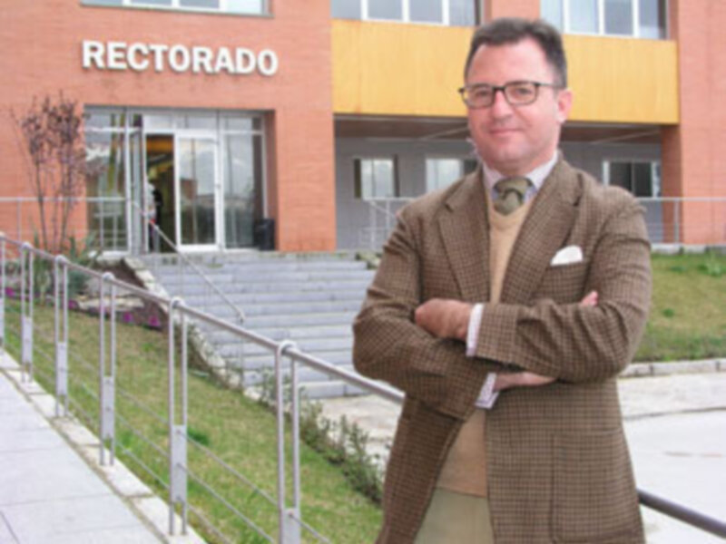Hombre en traje de cuadros frente al Rectorado de una institución educativa.