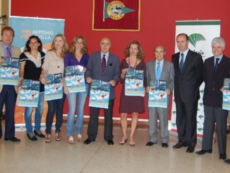 Presentación del evento 'Autismo Sevilla' con participantes sosteniendo carteles promocionales.