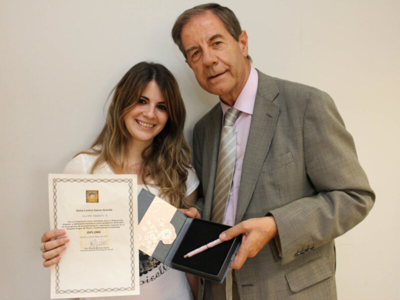 Persona recibiendo un diploma y un bolígrafo en una ceremonia formal.