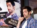 Un hombre con una camisa a cuadros posando frente a un cartel de un show llamado 'Dani Mateo'.