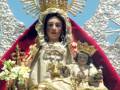 Imaginaria de la Virgen María con un niño en sus brazos, vestida con trajes dorados y rodeada de una corona y una capa roja.