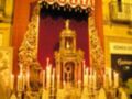 Una imagen de una iglesia con un altar adornado con velas y candelabros, iluminando la escena.