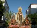 Estatua de la Virgen con velas y flores en un ambiente urbano.