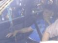 Un hombre en un taxi sostiene una cruz de rosario, mientras otros pasajeros observan desde el interior del vehículo.