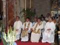 Celebración religiosa en iglesia, sacerdotes con hábitos blancos y vestimentas ceremoniales.
