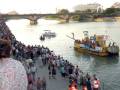 Celebración en el río con gente disfrutando y barcos en el agua.