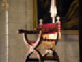 Un antiguo trono real, probablemente de una catedral o palacio histórico. El trono tiene un asiento rojo y detalles dorados, con una funda de terciopelo. Está situado en un entorno decorativo, posiblemente dentro de una iglesia o palacio.