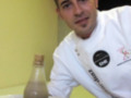 Un chef sonriendo en una cocina con un plato de frutos secos y una botella de aceite.