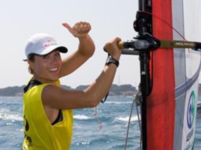 Una persona en un barco de vela, sonriendo y dándole el pulgar en el aire.
