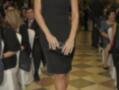Una mujer con vestido negro y tacones altos, posando en un evento formal.