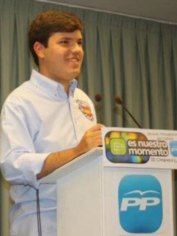 Un hombre en una presentación, con un fondo de cortinas y un logo de PP en el fondo.
