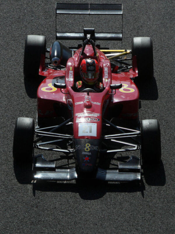 Vehículo de carreras rojo en pista de asfalto, vista desde arriba.
