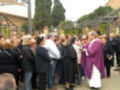 Una procesión religiosa con una persona vestida de morado y un círculo de personas en trajes formales observando.