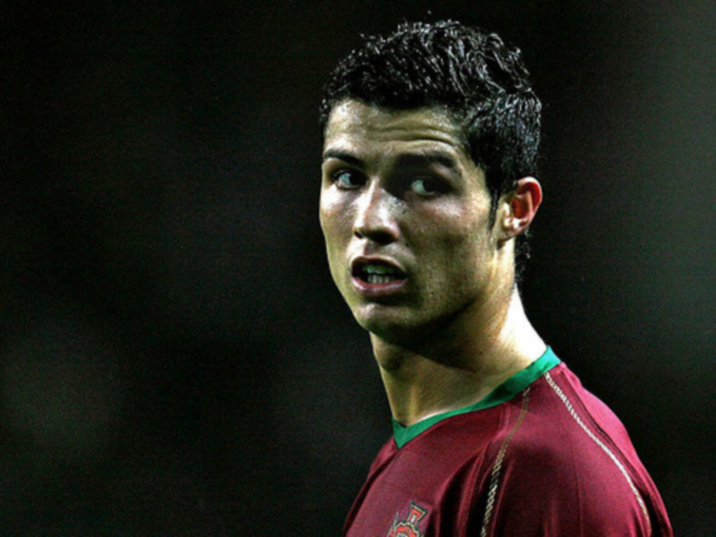 Jugador de fútbol en acción, vestido con la camiseta de Portugal, en un entorno deportivo nocturno.