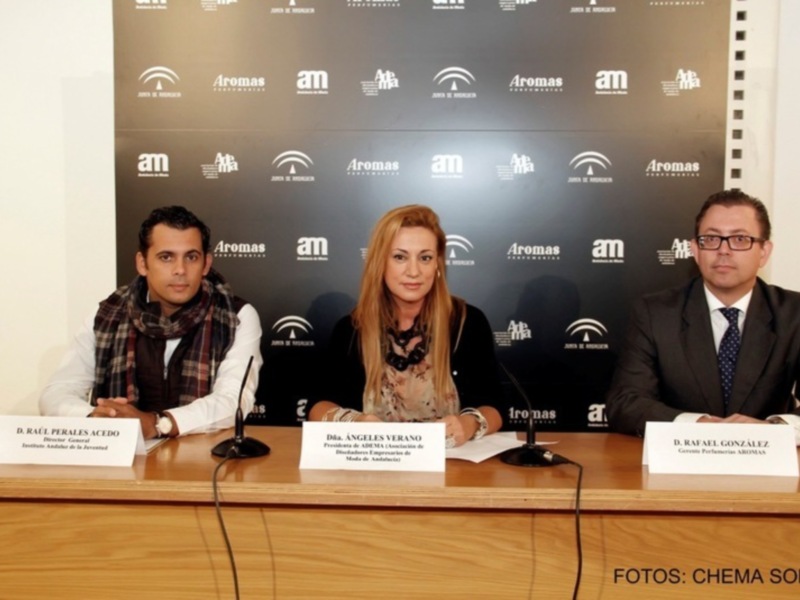 Tres personas sentadas en una mesa de rueda de prensa con logos de 'Aromas' y 'am' en el fondo.