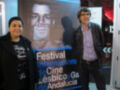 Dos personas posan frente a un póster del Festival Internacional de Cine Lésbico y Gay de Andalucía.