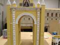 Modelo de arco decorativo en proceso de pintura, con detalles arquitectónicos y una imagen central.