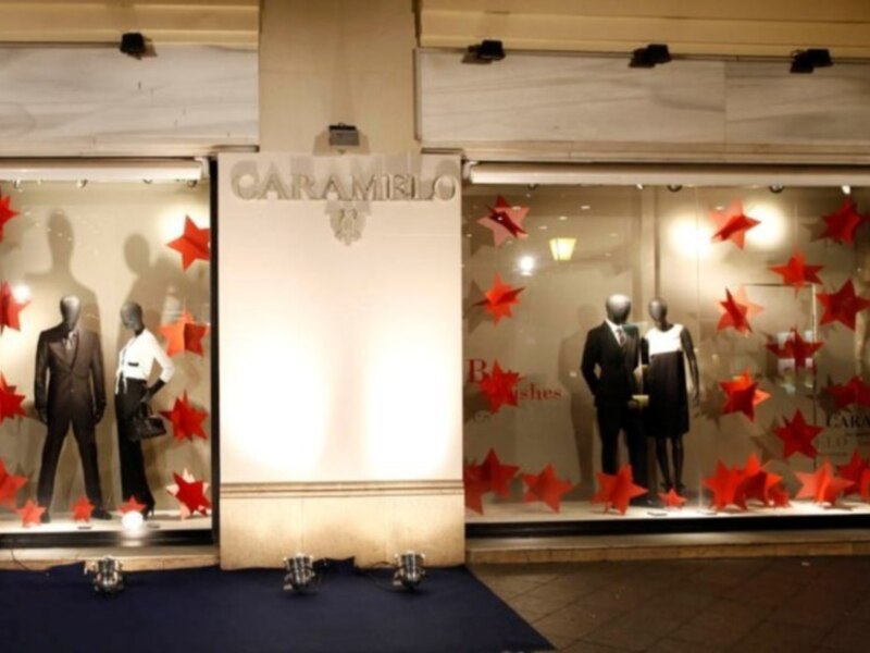 Tienda de ropa con maniquíes y decoración navideña con estrellas rojas.