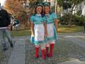 Dos niñas con vestidos azules y faldas blancas, posando en un parque.
